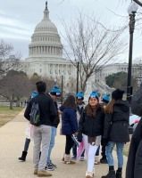 People gathered on a walkway near the U.S. Capitol on a cloudy day.