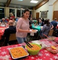 Woman serving food at a buffet table in a crowded community hall