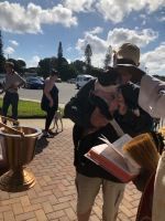 People at an outdoor gathering beside a brick path and brass urn under a cloudy sky