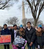 Group of people holding signs during a protest, with the Washington Monument in the background.