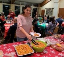 Woman serving food from a buffet table at a festive indoor gathering