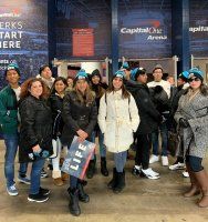 Group of people posing outside Capital One Arena at night, wearing coats and winter hats.