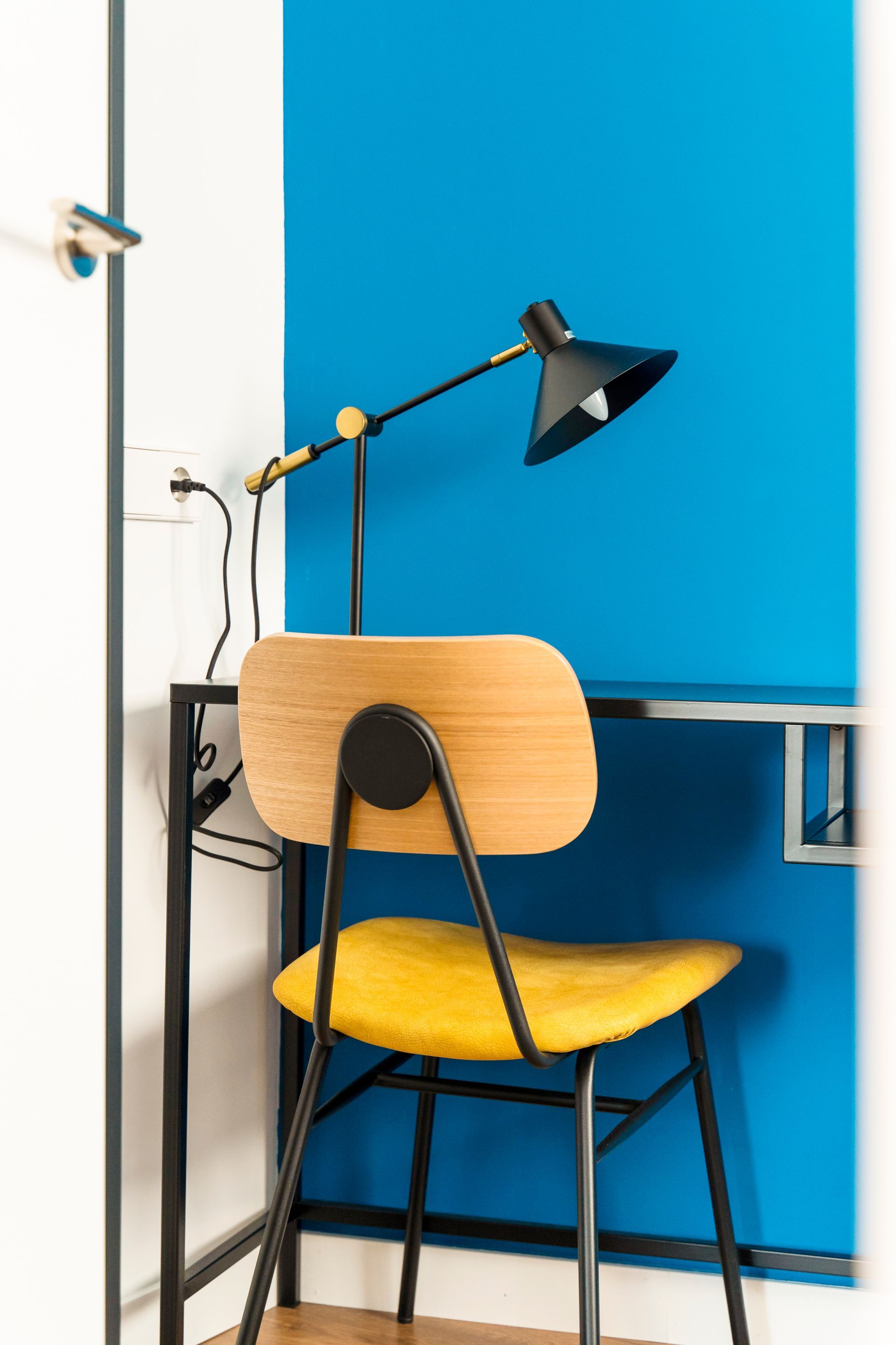 A yellow chair is sitting next to a desk with a lamp.