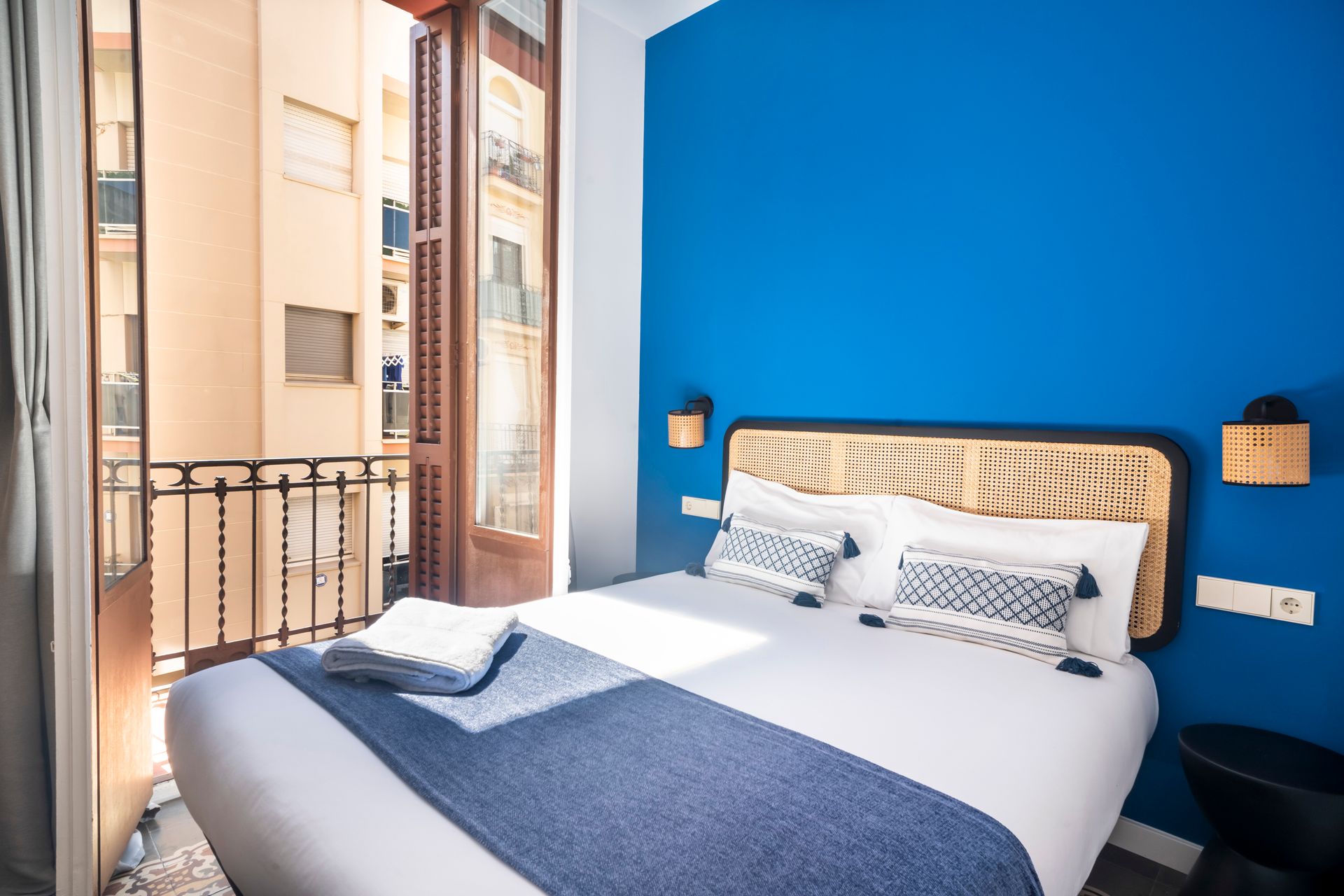 A hotel room with a bed , balcony and blue walls.