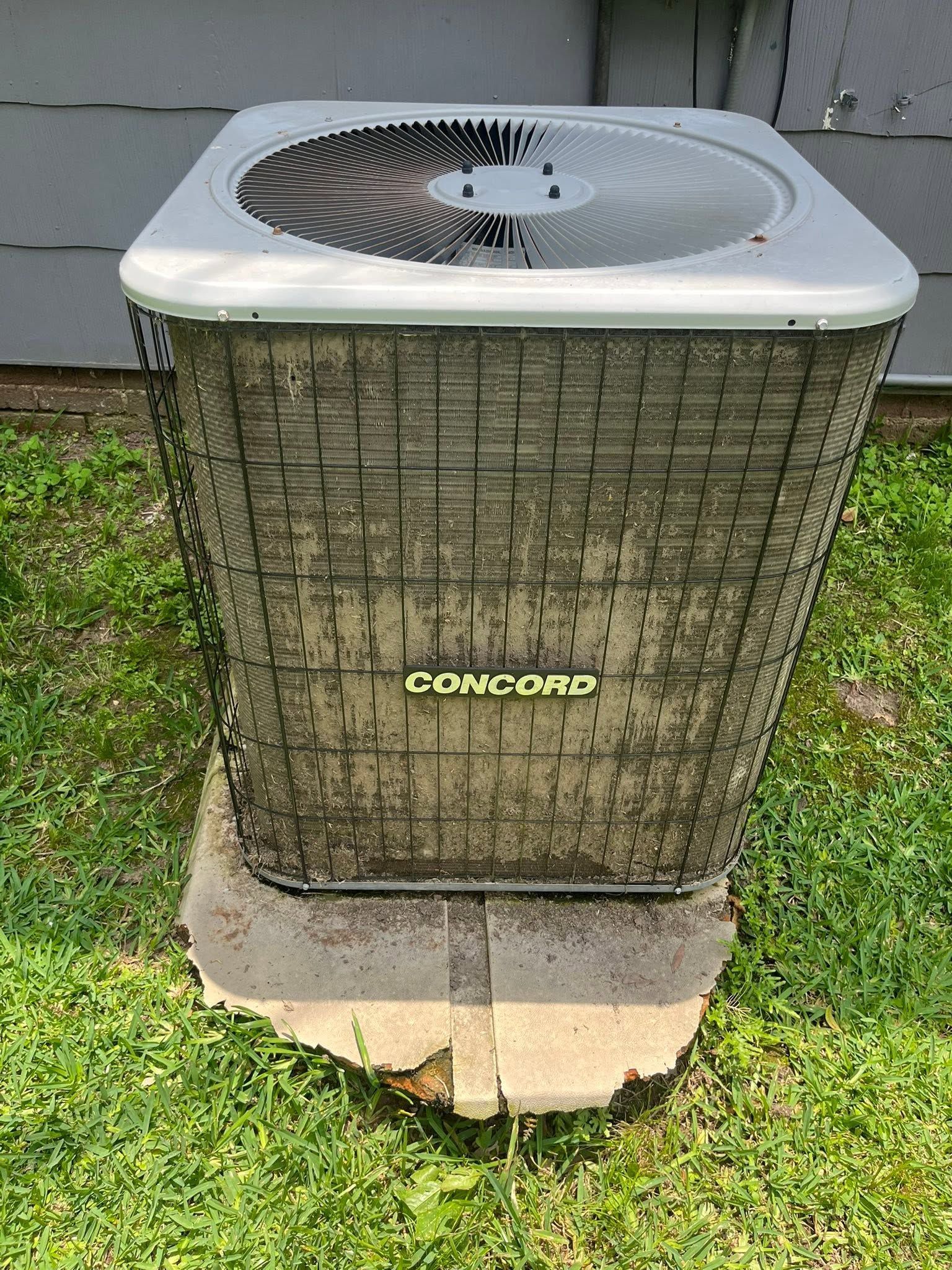 Outdoor air conditioner unit on a concrete pad in a grassy yard