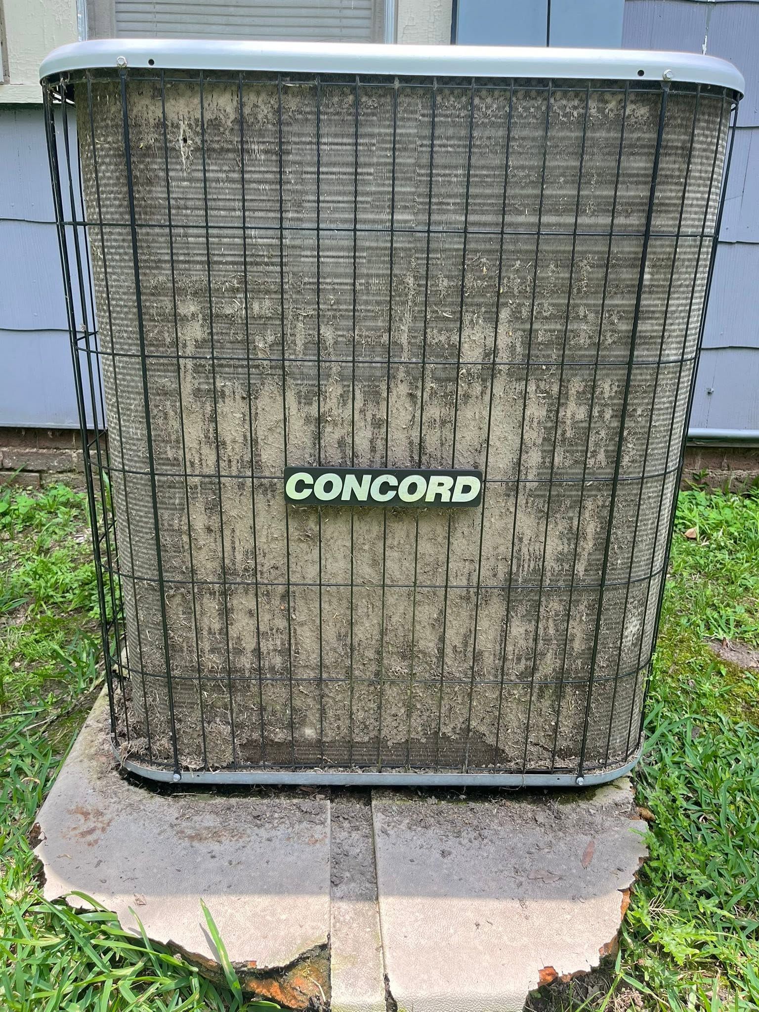 Outdoor air conditioner unit with a faded grille and Concord logo on a concrete pad.