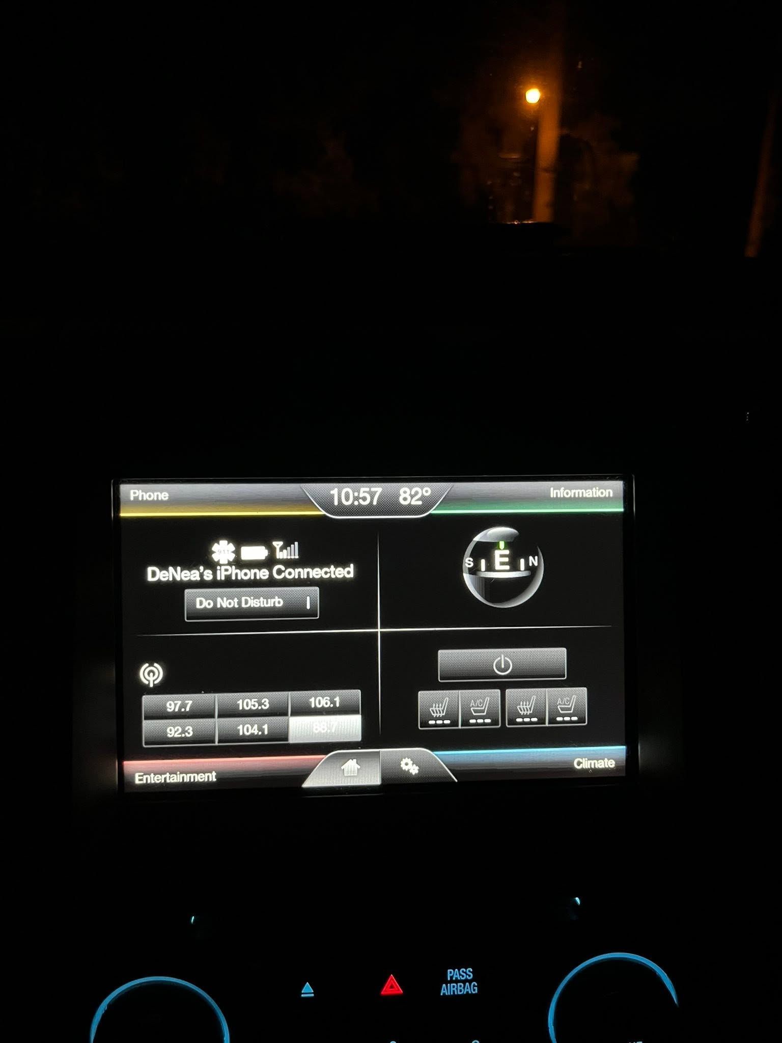 Car dashboard at night showing a GPS/navigation screen with illuminated controls and a dim road ahead.