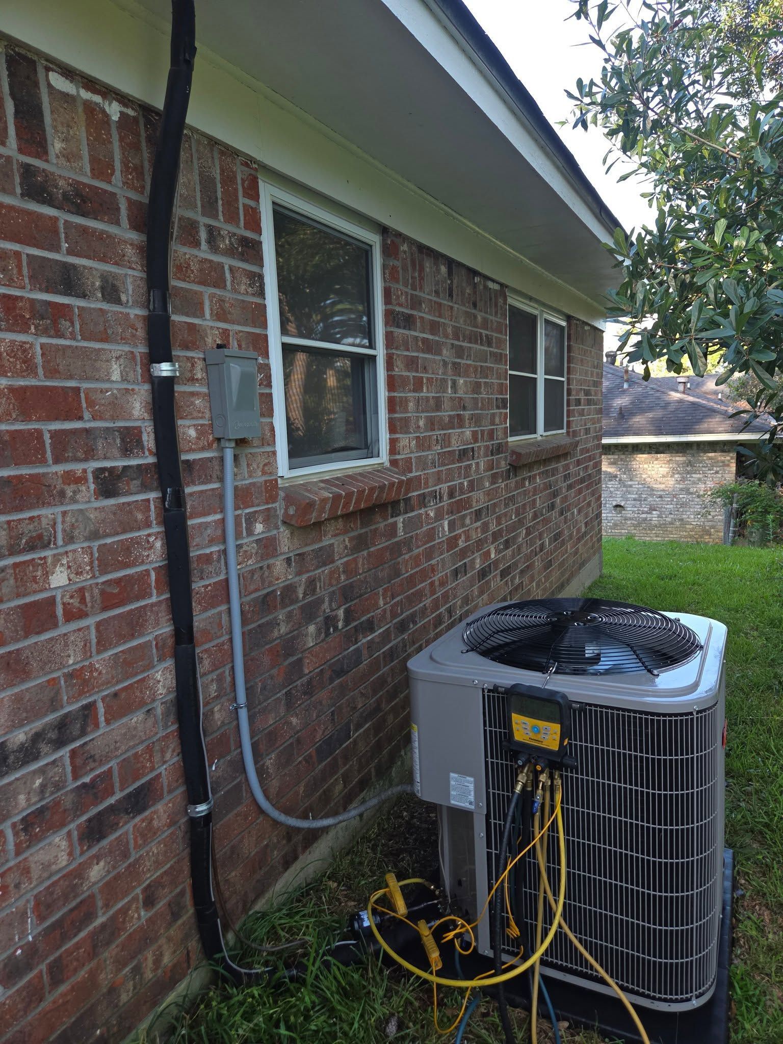 Brick house exterior with a window, utility meters, and a central air conditioner unit on the side yard