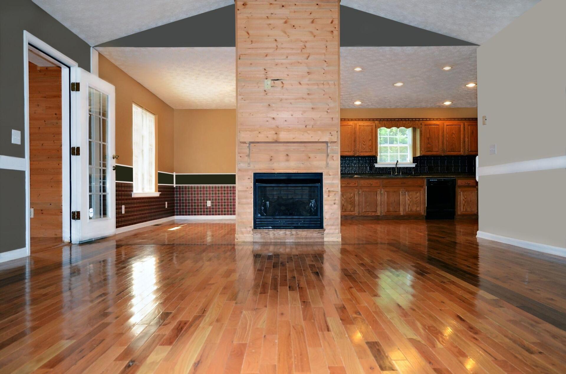 An empty house with hardwood floors and a fireplace
