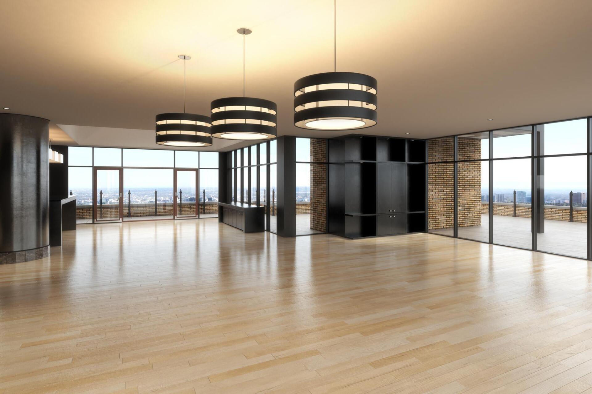 A large empty room with wooden floors and lots of windows