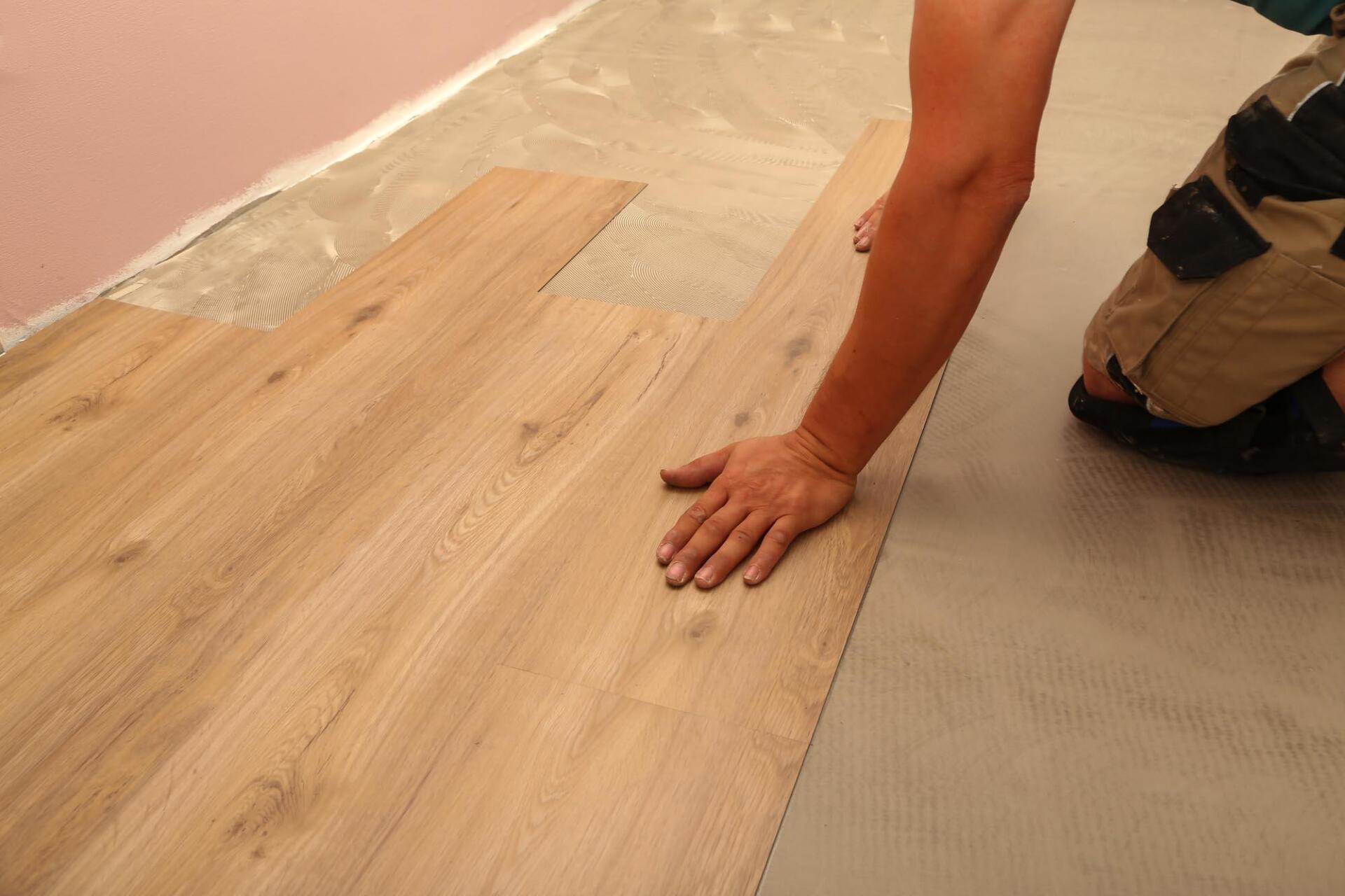 A person is installing a wooden floor in a room.