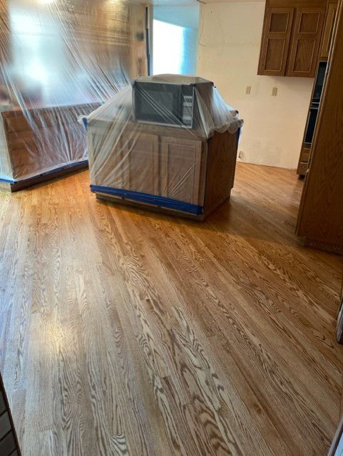 A kitchen with hardwood floors and a microwave covered in plastic.