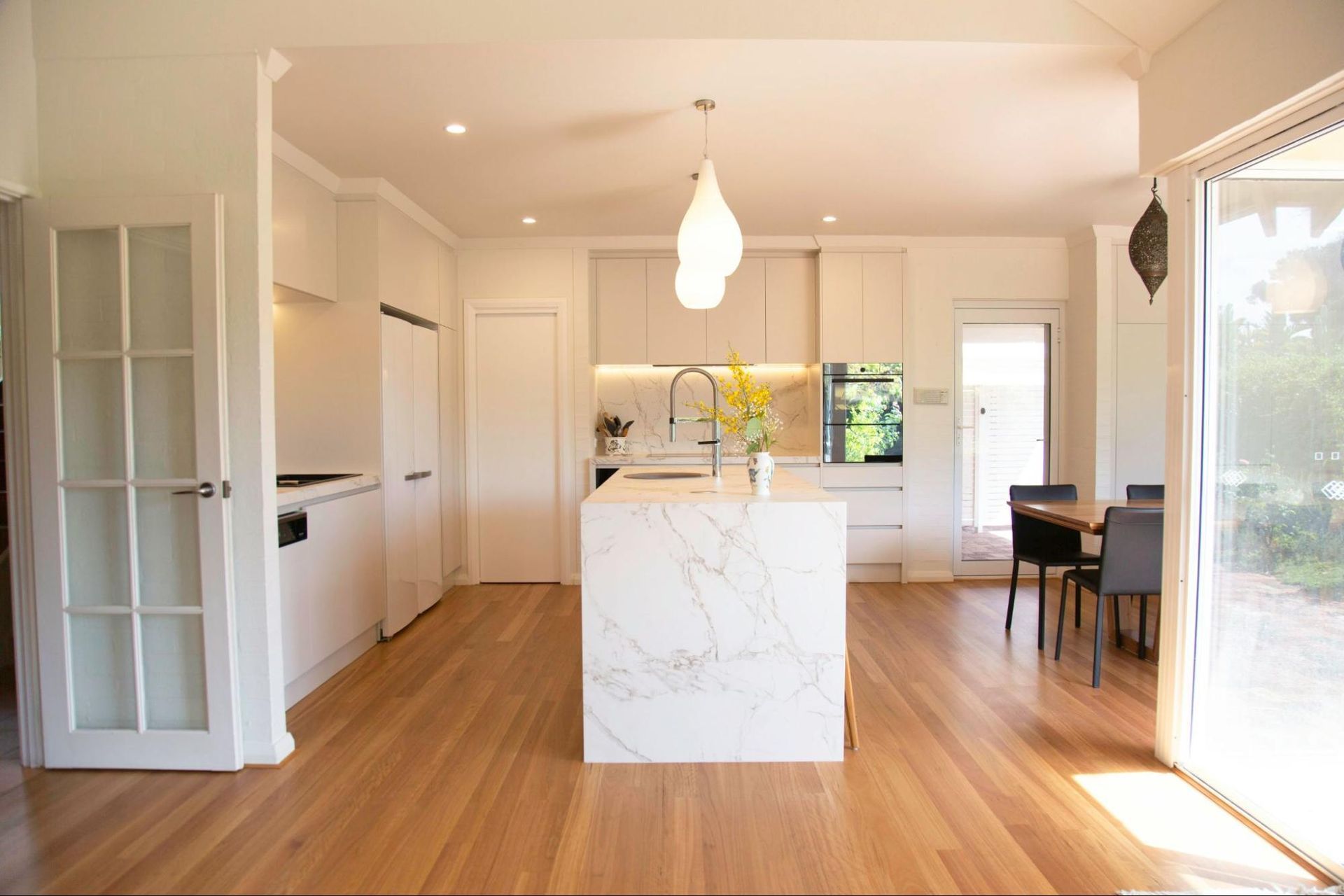 A kitchen with white cabinets and a large island in the middle