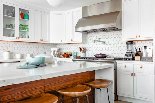 White kitchen with wood island, white cabinets, and stainless steel range hood.