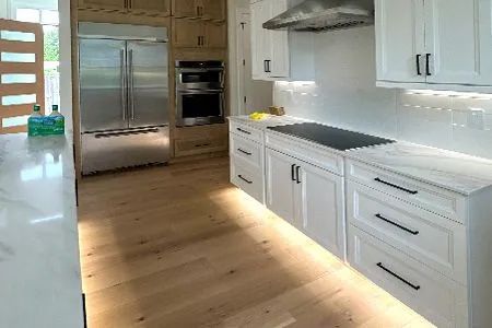 Kitchen with white cabinets, stainless steel appliances, and light wood floors.