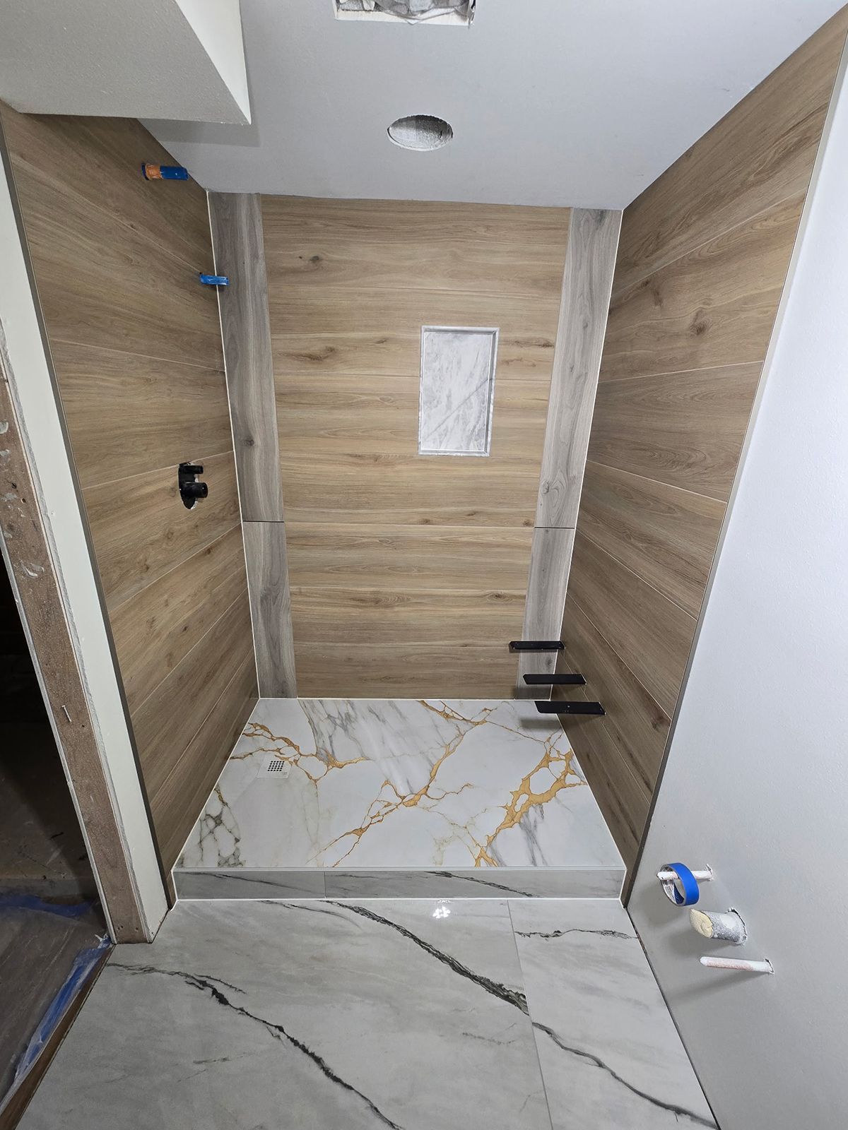 A bathroom with a walk in shower with wooden walls and a marble floor.