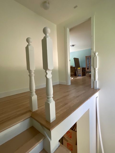 A wooden staircase with white railings leading to a living room