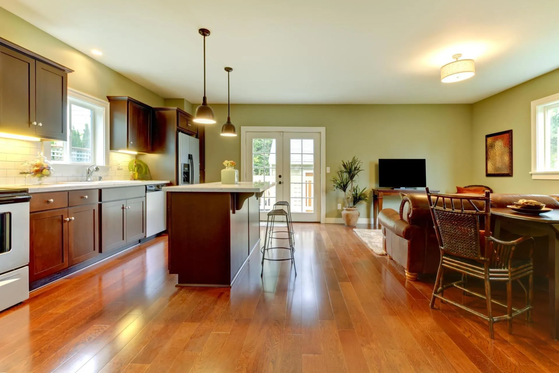 Open-concept kitchen and living area with dark wood cabinets, hardwood floors, and olive green walls.
