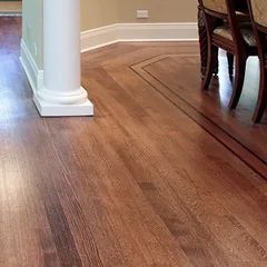 Hardwood floor with a dark border in a room, with a white column on the left and a chair on the right.
