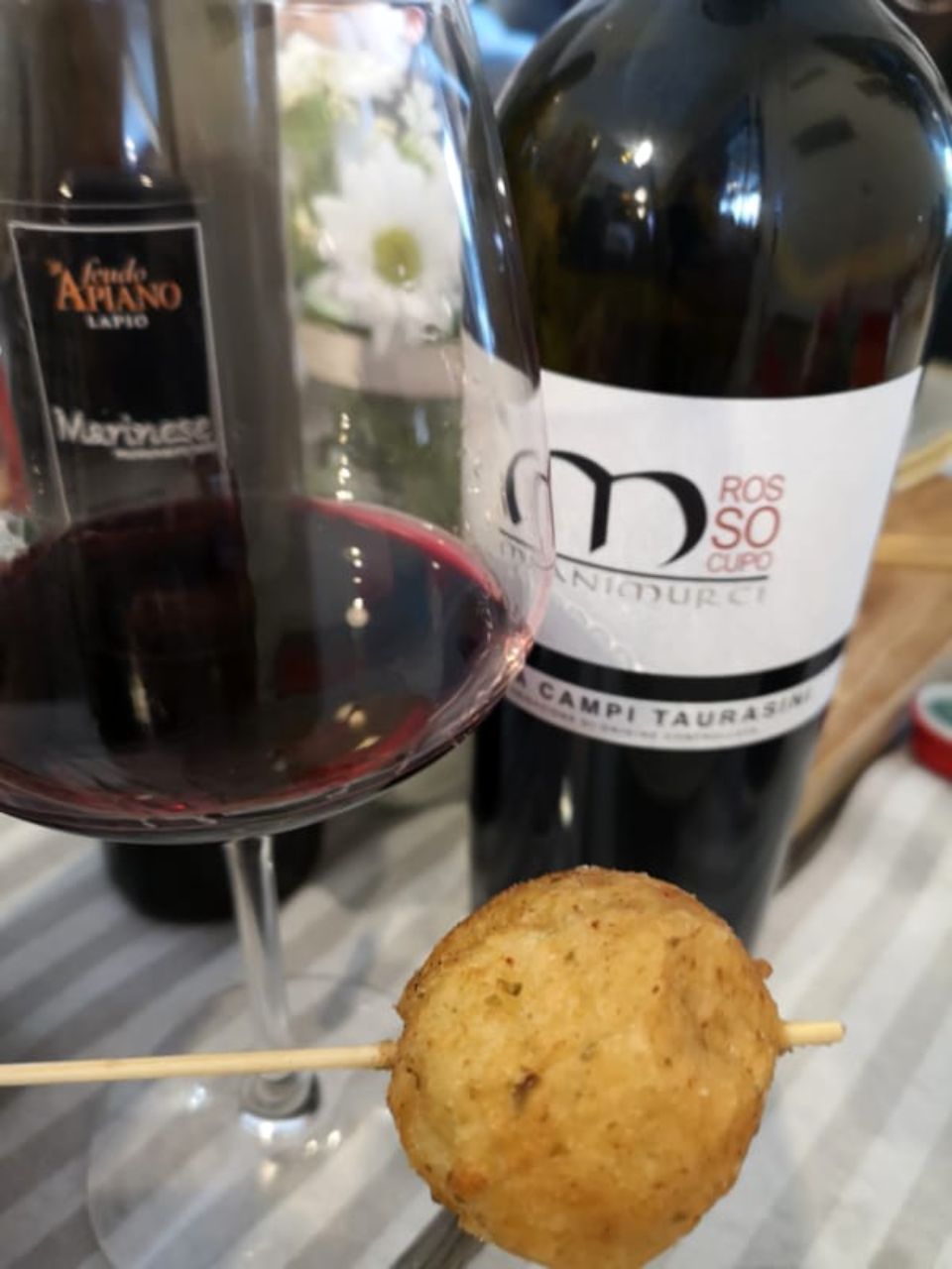 Calice di vino rosso con spiedino e bottiglia accanto
