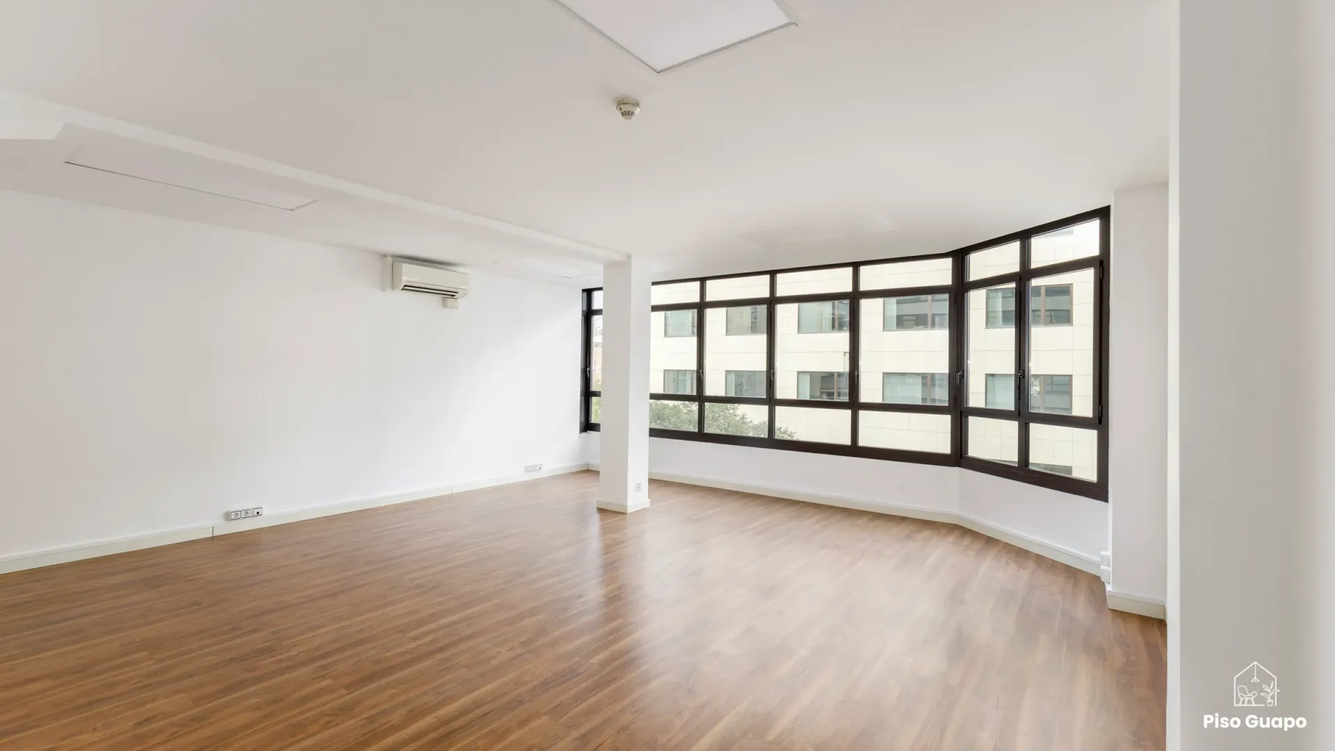 Fotografía inmobiliaria de salón diáfano con ventanales panorámicos en Barcelona.