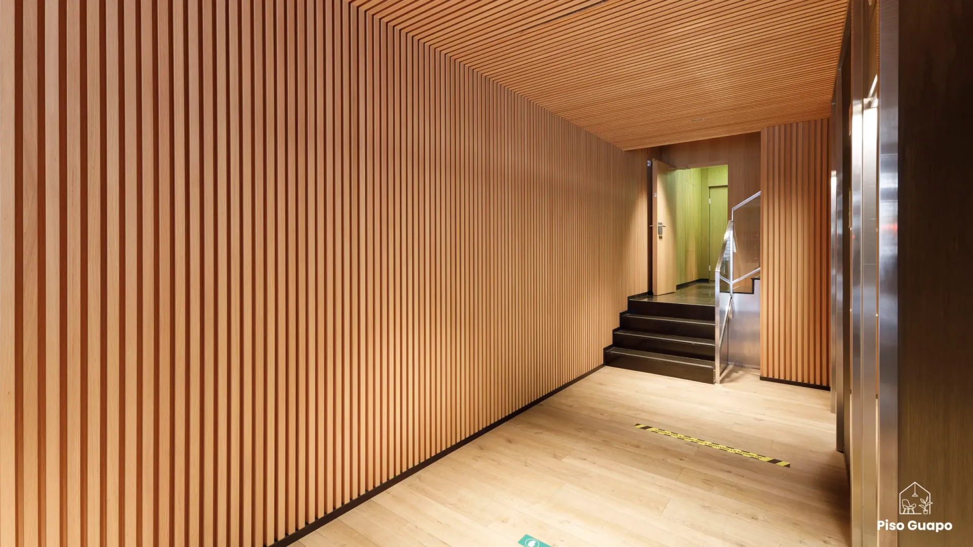 Fotografía inmobiliaria de acceso interior con revestimiento de madera en Barcelona