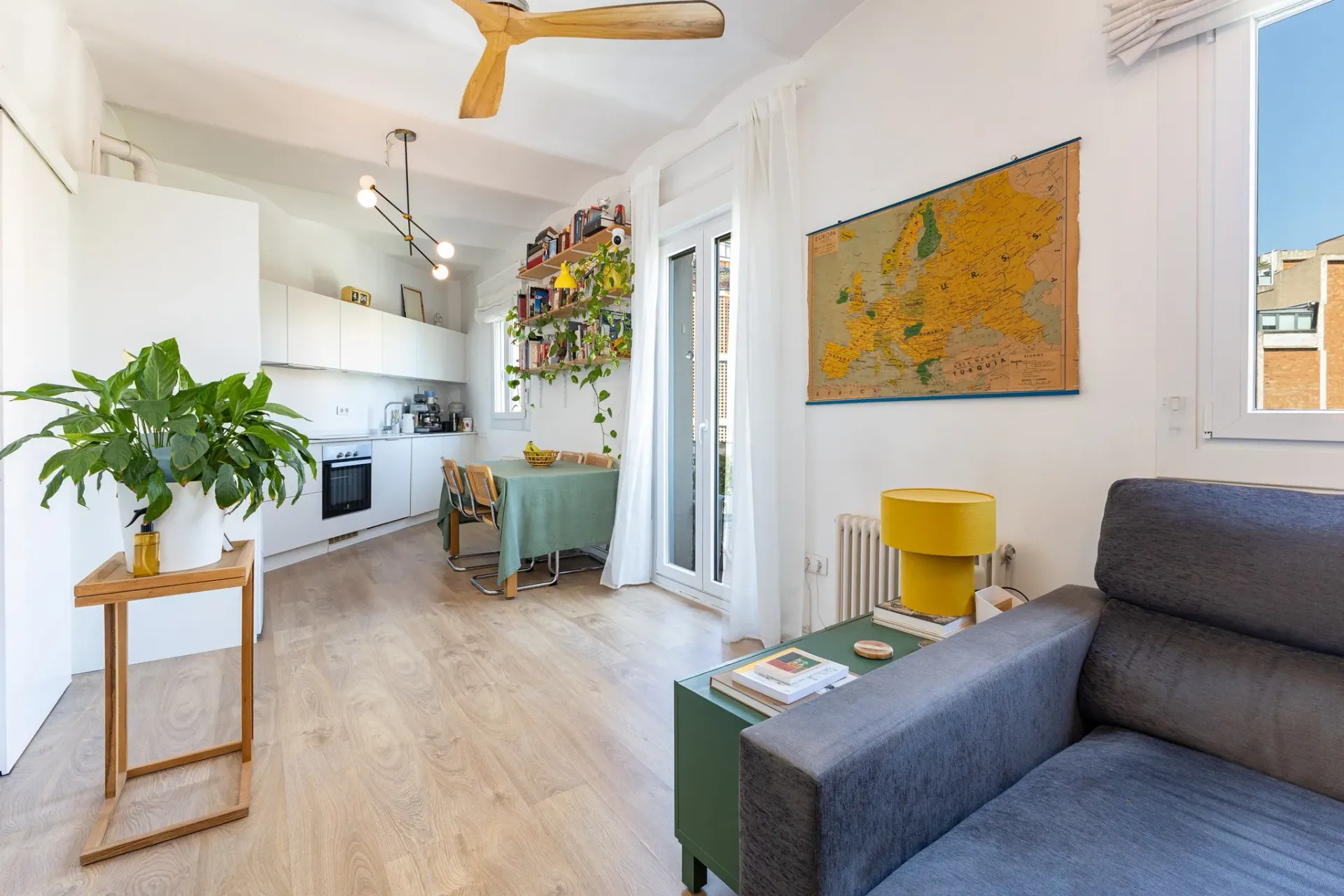 Fotografía inmobiliaria de salón luminoso con cocina abierta y comedor en vivienda reformada