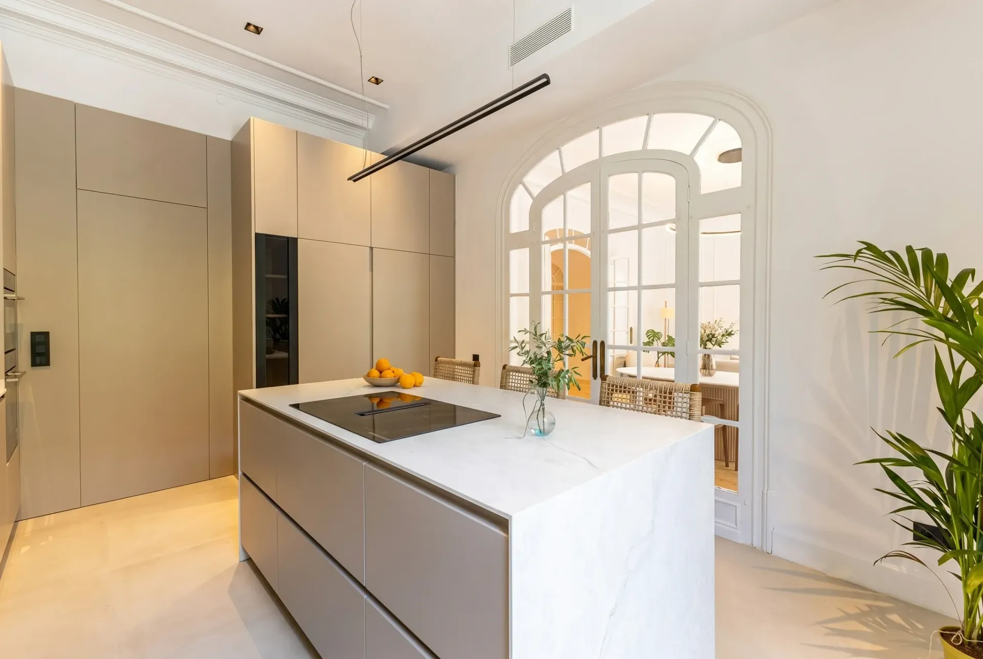 Render inmobiliario de cocina de diseño con isla de mármol, armarios integrados y puertas arqueadas
