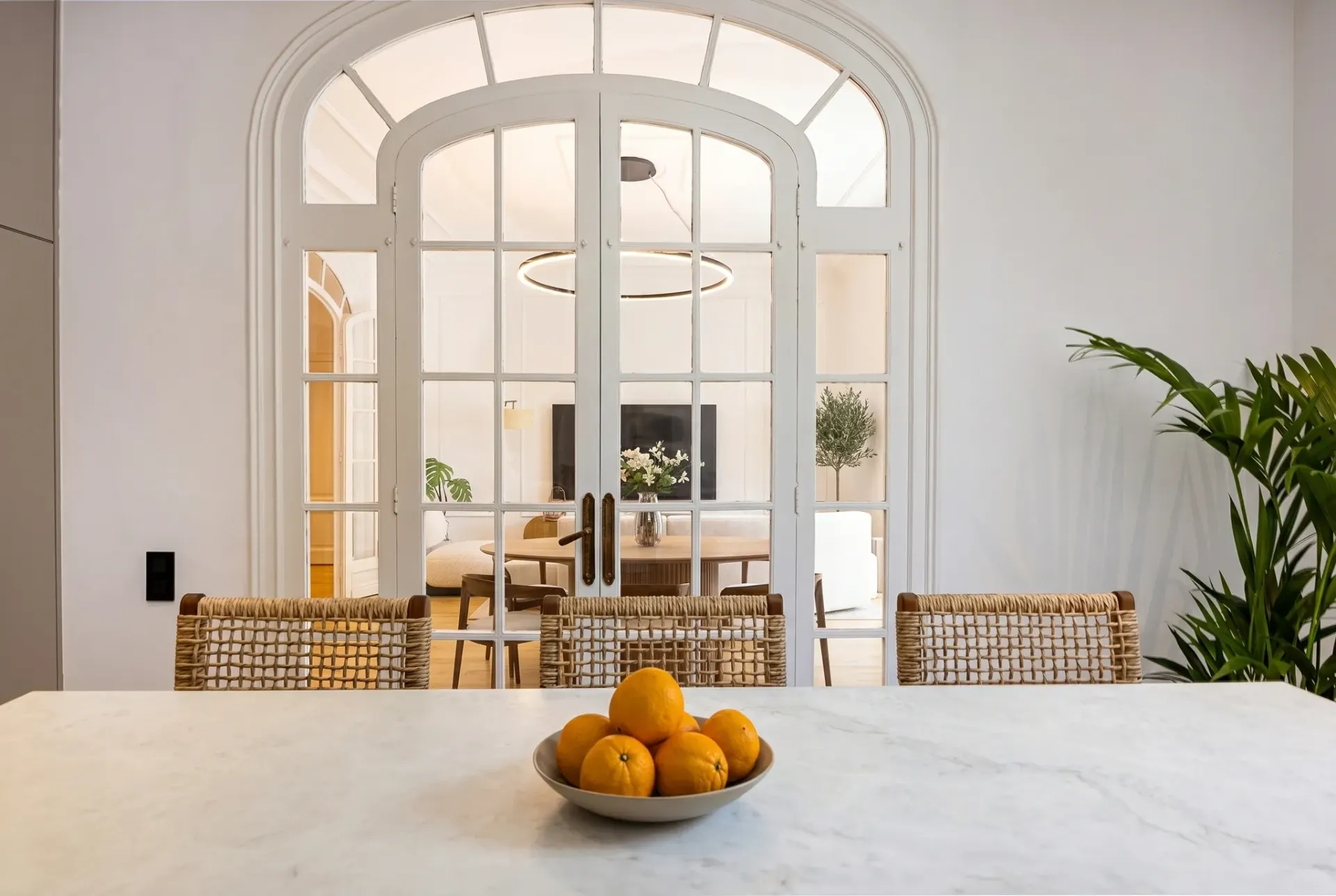 Render inmobiliario de cocina comedor con puertas acristaladas de arco y mesa central