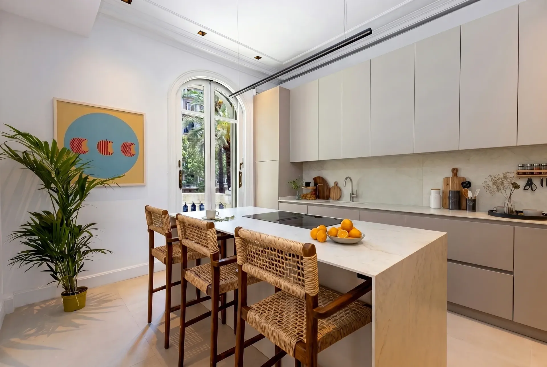 Render inmobiliario de cocina luminosa con isla central y taburetes de madera