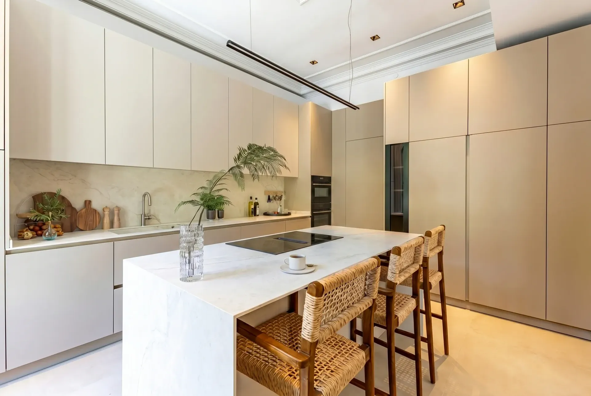 Render inmobiliario de cocina de diseño con isla central, encimera de mármol y taburetes altos