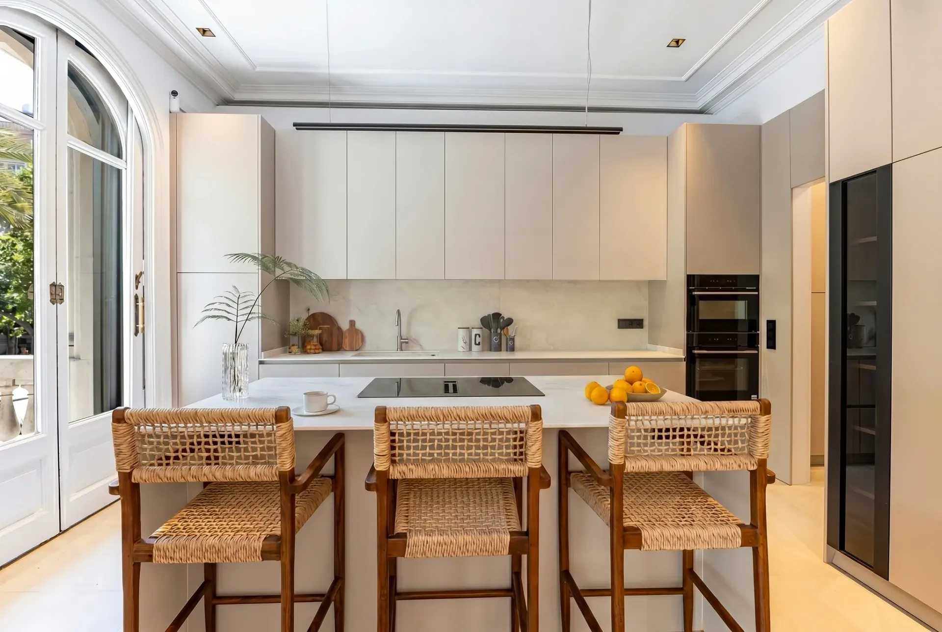 Render inmobiliario de cocina moderna con isla de mármol, taburetes de fibra y armarios integrados