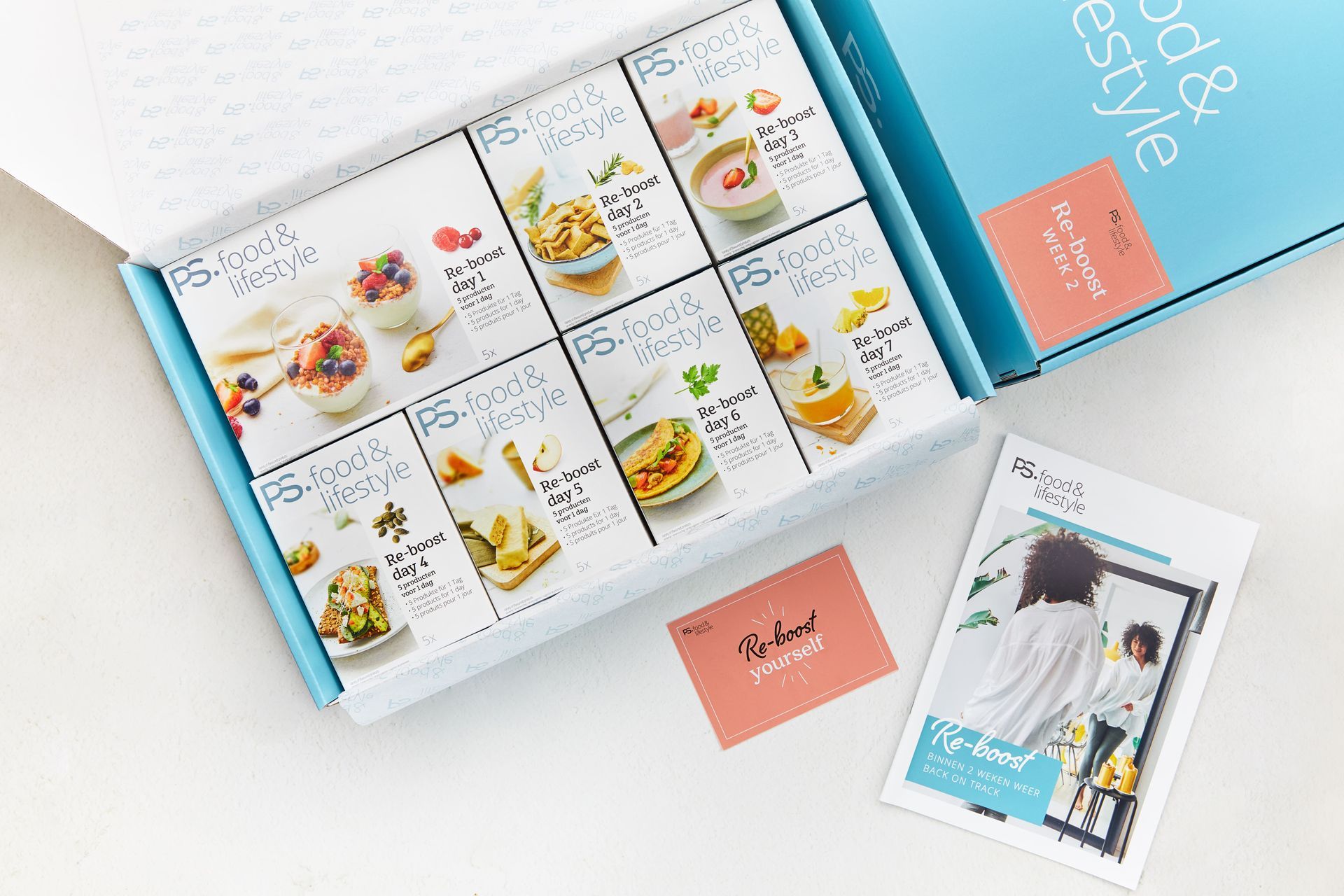 Een abonnementsbox met receptenkaarten, een roze kaart en een brochure op een witte ondergrond.