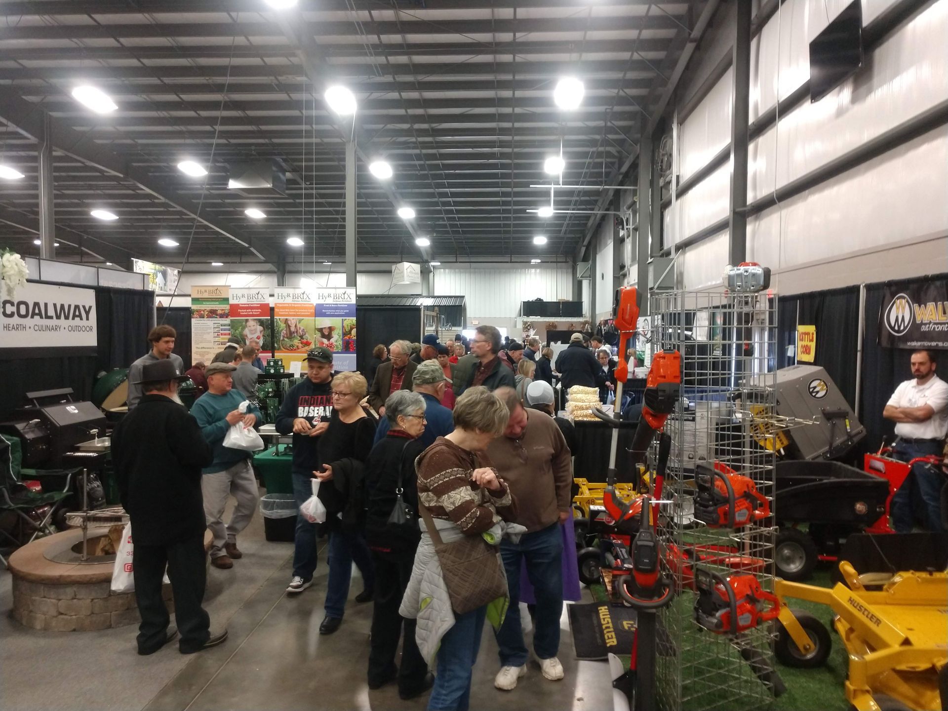 Indoor trade show with a crowd viewing lawn care equipment.