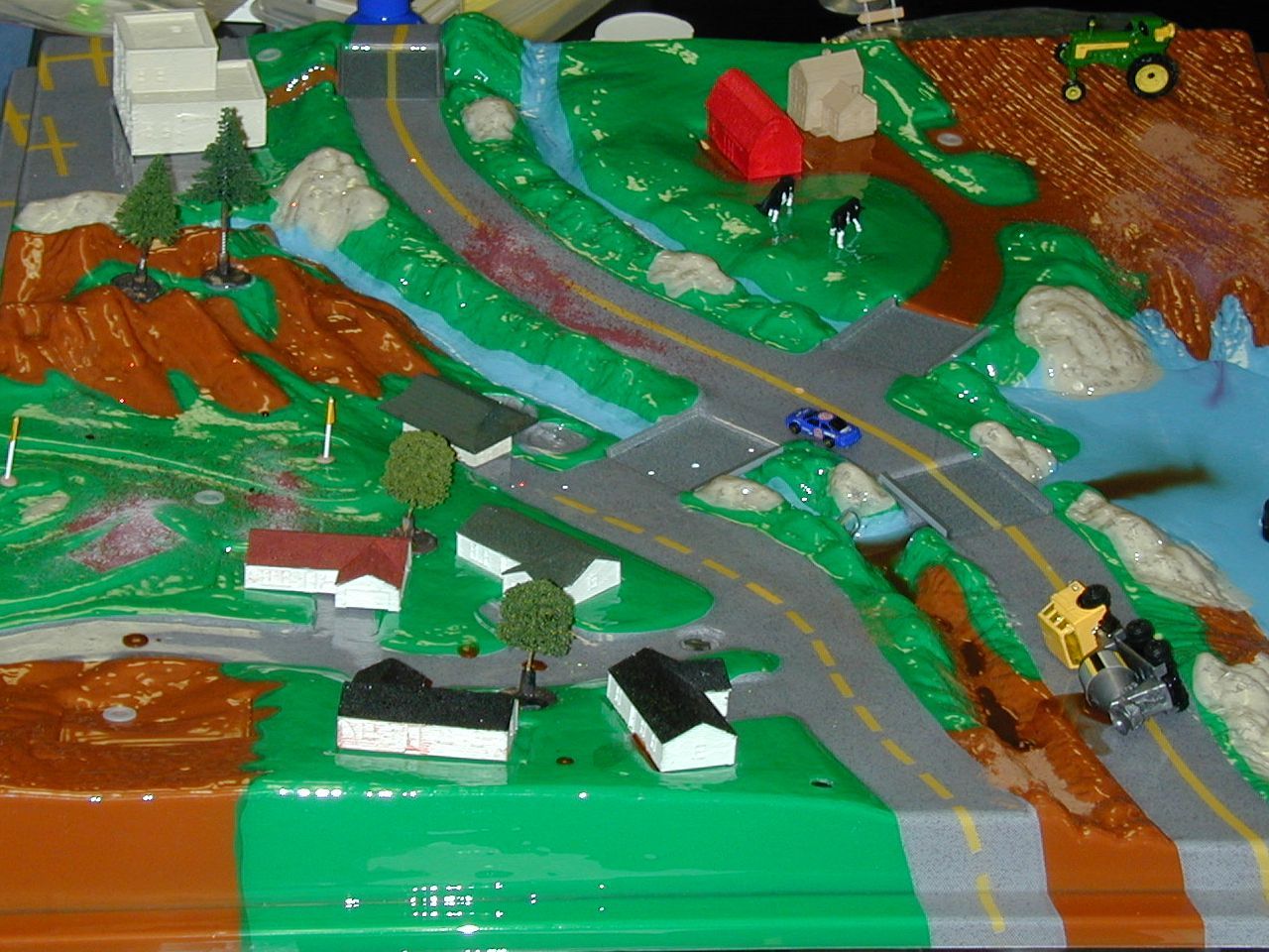 The enviroscape hazardous materials model- Toy farm landscape with roads, barn, tractors, river, and hills in bright colors