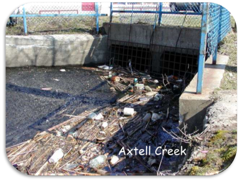 Trash and debris clogged in a concrete storm drain labeled “Axtell Creek”