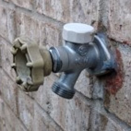 Outdoor wall faucet with a white cap showing built in backflow prevention.