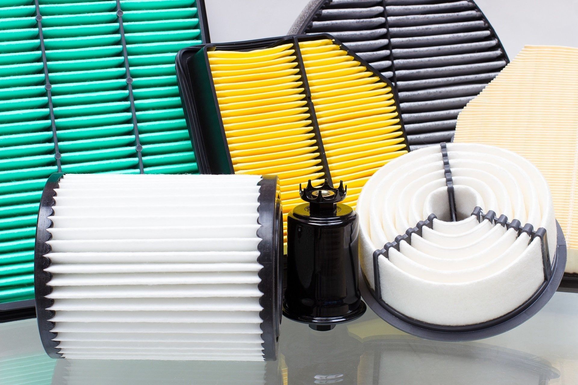 Assorted colorful pleated air filters displayed on a reflective surface