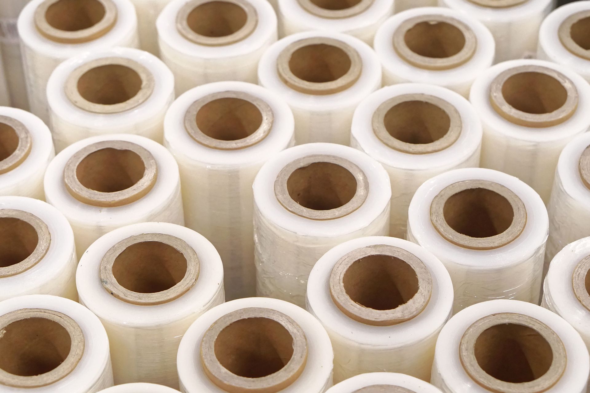 Stacks of clear adhesive tape rolls with white cores, tightly packed together