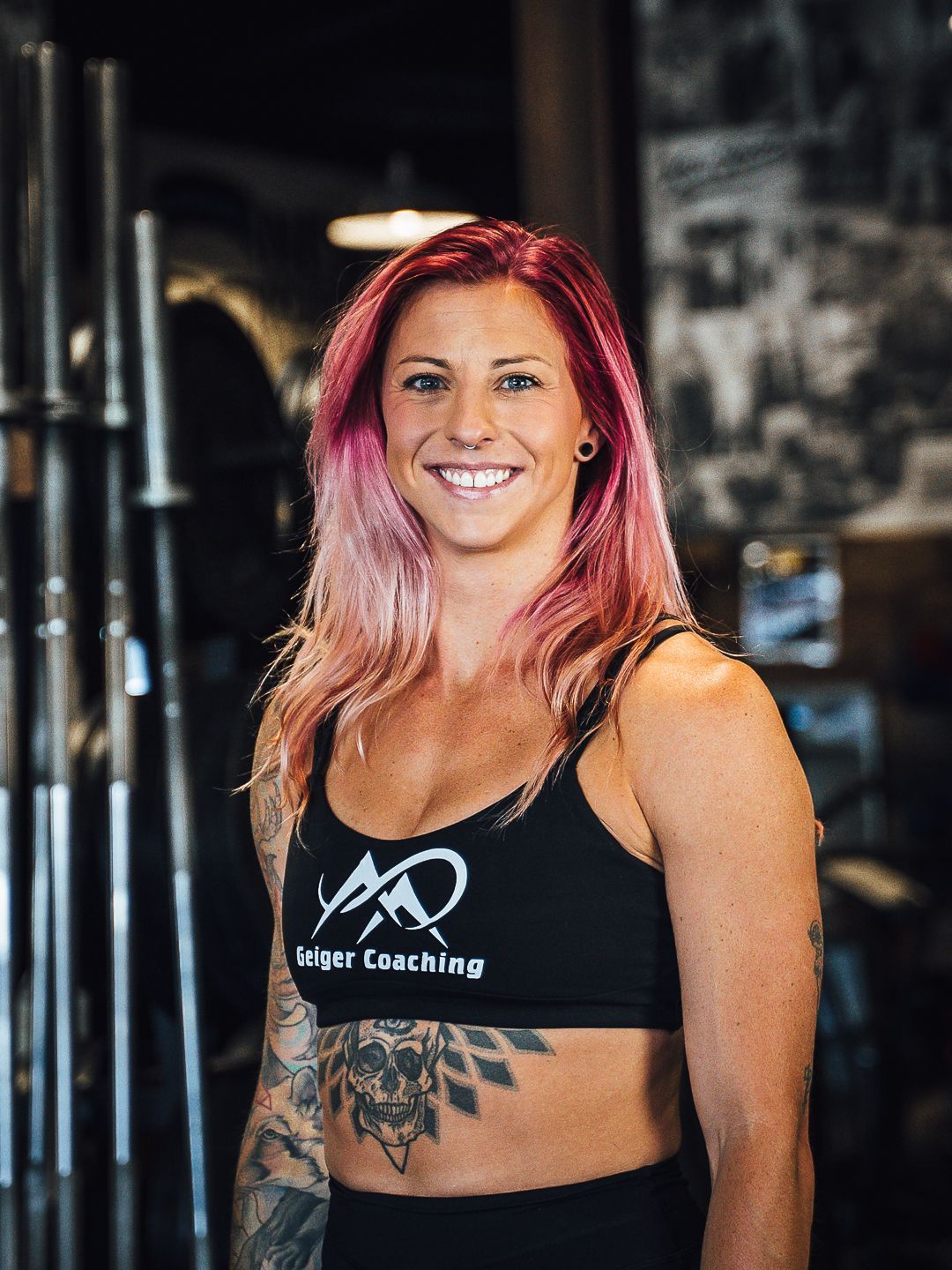 Woman with pink hair, wearing a black sports bra with