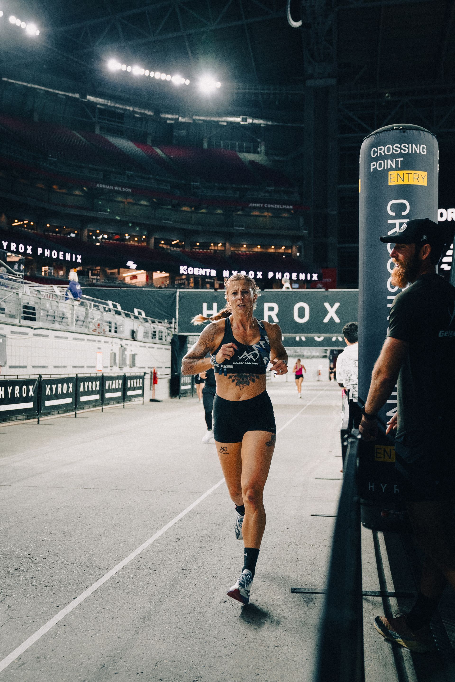 Female runner in black crossing the finish line inside a stadium during a race