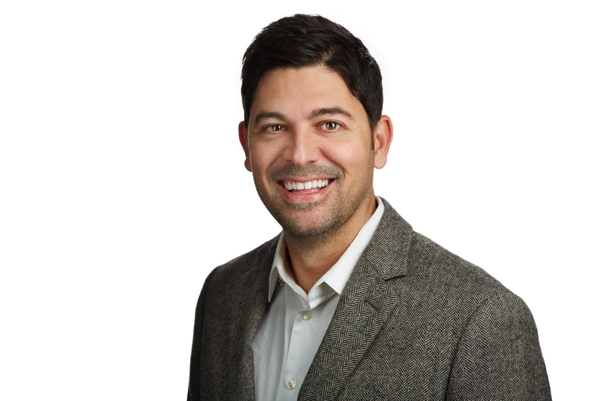 A man in a suit and white shirt is smiling for the camera.