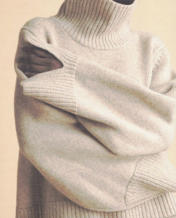 Persona che indossa un maglione dolcevita di colore chiaro e tiene le braccia incrociate.