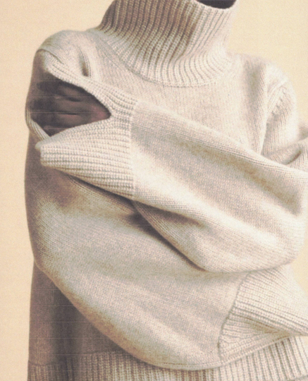 Persona che indossa un maglione dolcevita di colore chiaro e tiene le braccia incrociate.