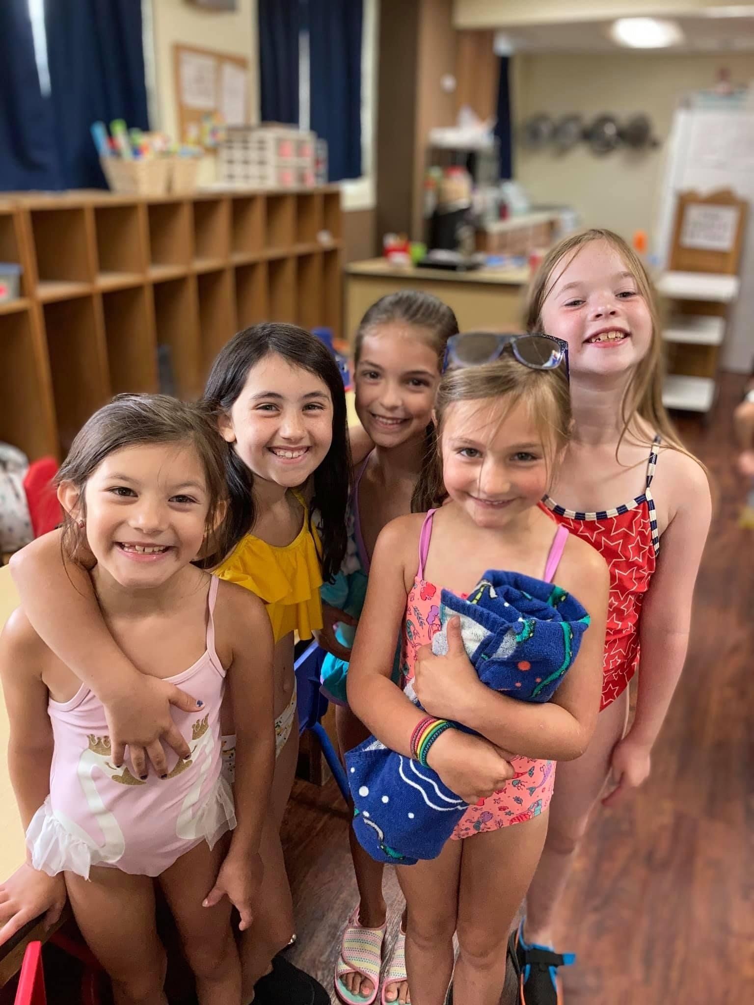 5 Young girls smiling for a photo at their preschool