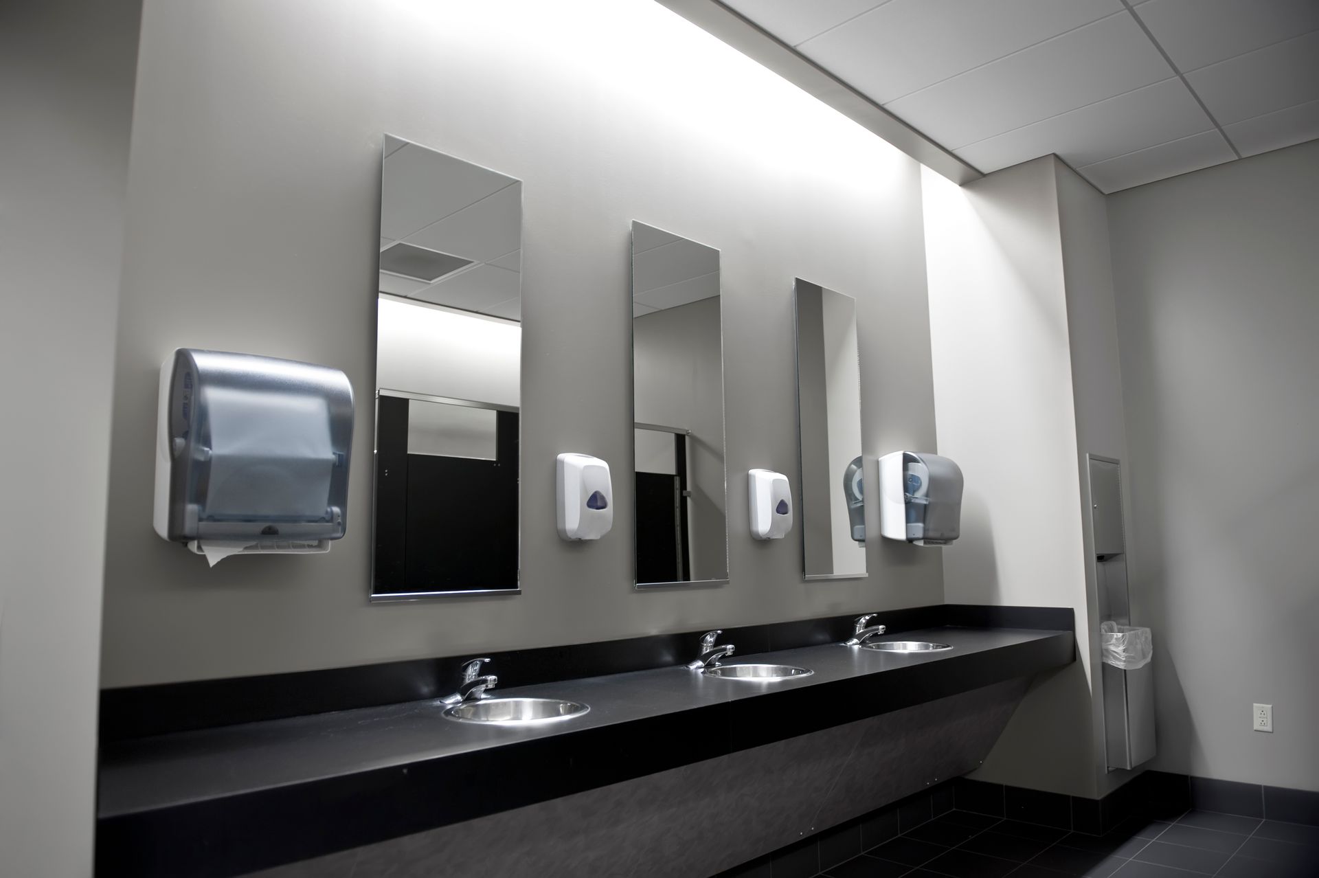 A bathroom with a row of sinks and mirrors