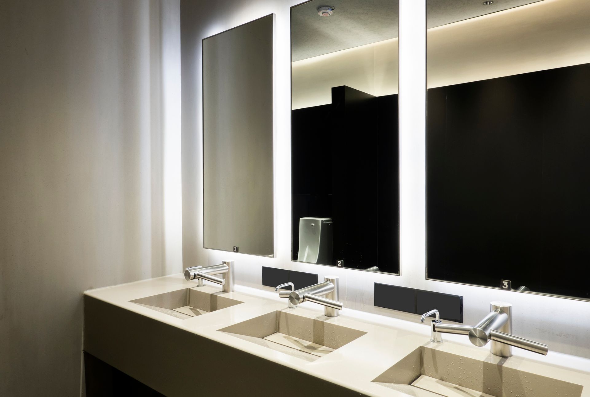 A bathroom with three sinks and two mirrors