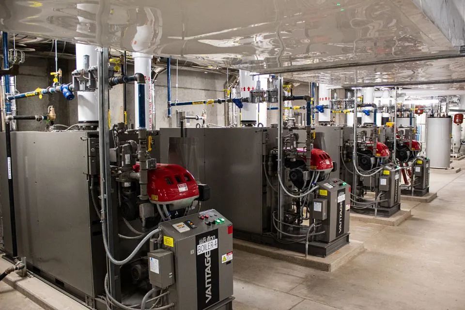 Industrial boiler room with red pumps, pipes, and metal equipment in a mechanical basement room