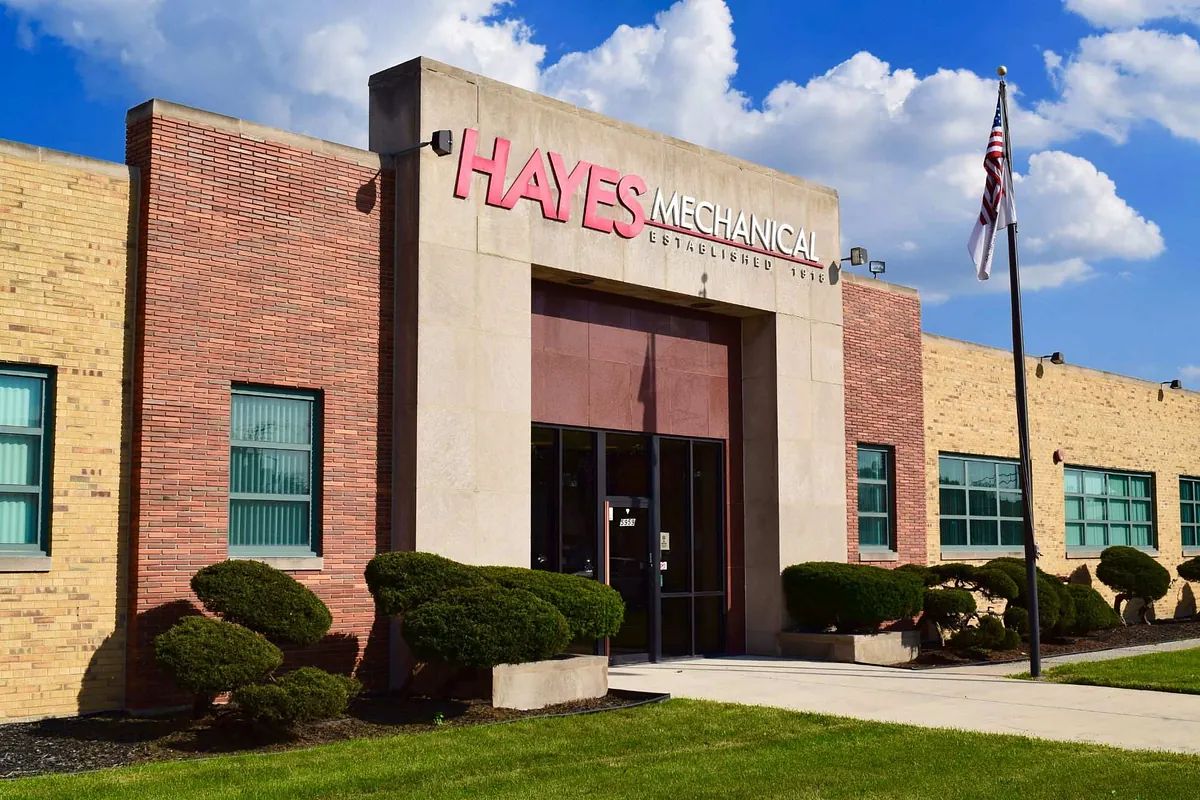 Hayes Mechanical building entrance with brick facade, trimmed shrubs, and an American flag outside