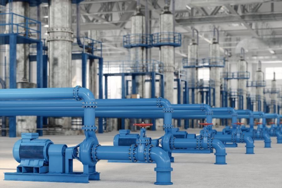 Blue industrial pipes and pumps in a large factory facility
